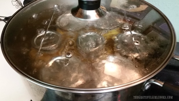 Los tarros de relleno de tarta de melocotón se procesan en un enlatador al baño María.