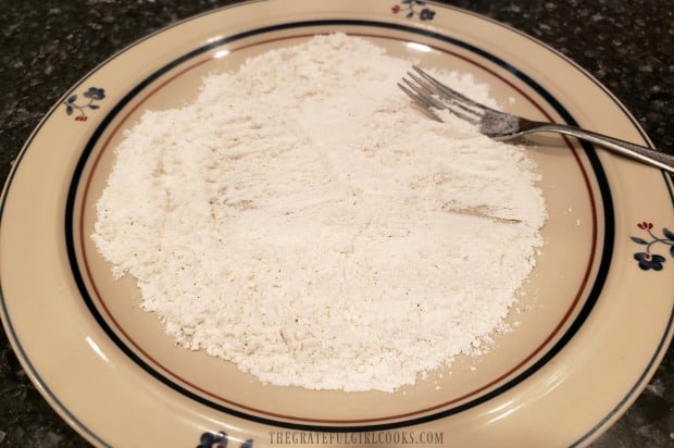 Flour and seasonings are placed on a plate to dredge the cod fillets in before cooking.