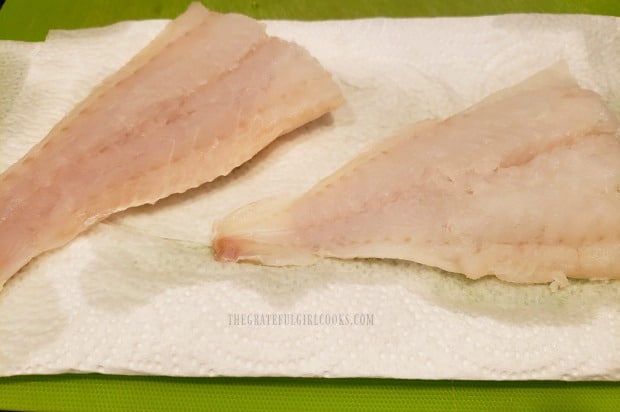 The cod fillets (for lemon piccata cod) are rinsed and dried before coating in flour.