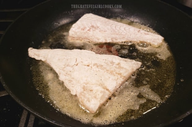 The floured, seasoned cod fillets are cooked in butter in large skillet.