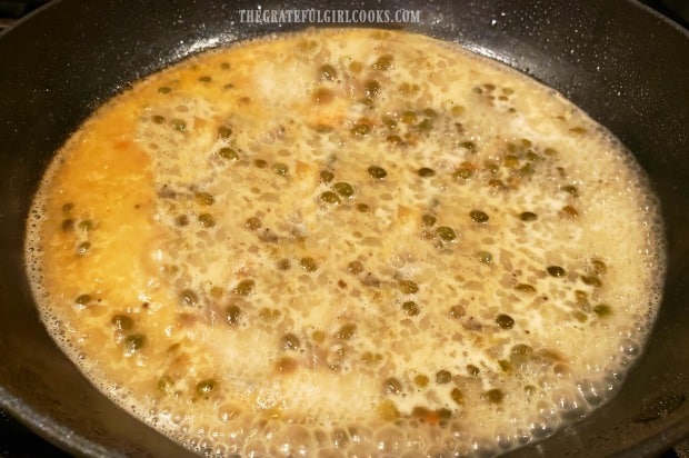 The lemon piccata sauce with capers cooks in a large skillet.