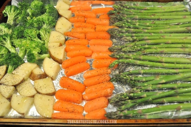 Veggies are placed on aluminum foil on baking sheet, then seasoned before roasting.