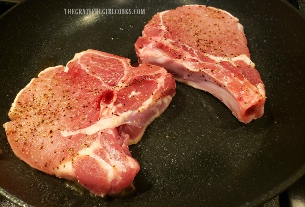 Pork chops are pan-seared in a skillet before adding the glaze.