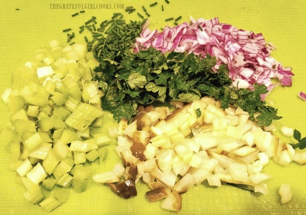 Celery, parsley, red onion, and dill pickles are chopped to add to tuna salad.