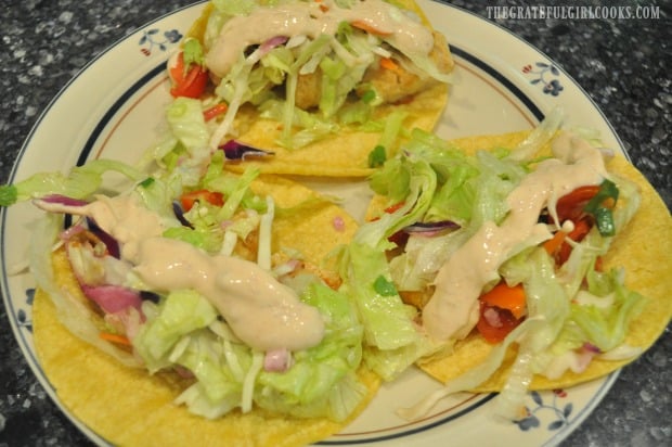 Baja fish tacos are topped with slaw salad and sauce before serving.