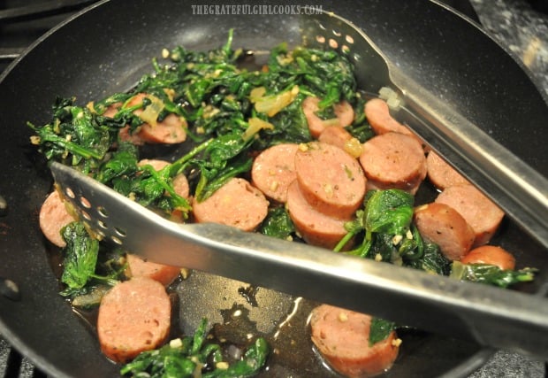 Cooked chicken sausage slices are added to the skillet with the spinach.