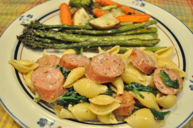 Each portion of chicken sausage and spinach pasta is sprinkled with Parmesan cheese.