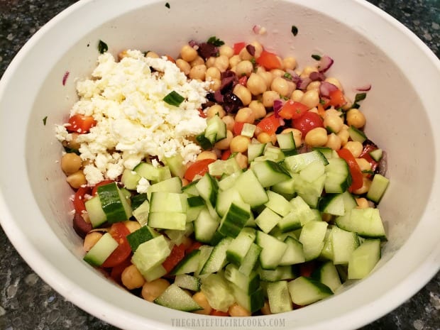 Feta cheese and diced cucumbers are added to the Greek garbanzo salad before serving.