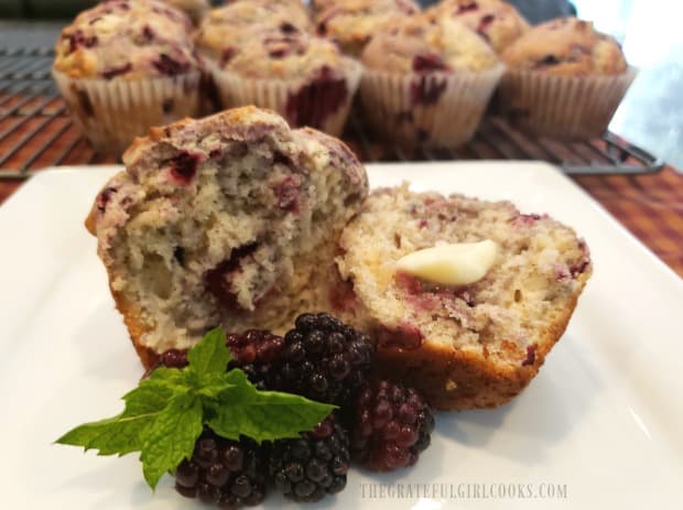 One of the blackberry muffins, cut in half, served with butter.