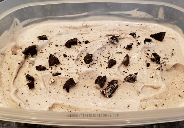 Cookies n' cream ice cream is transferred to a container, and put in kitchen freezer to firm up.