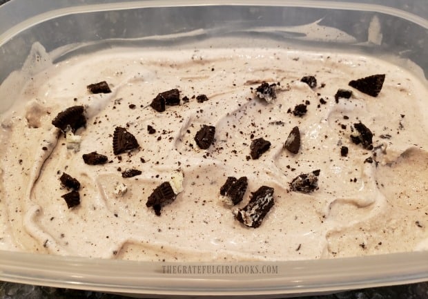 Cookies n' cream ice cream is transferred to a container, and put in kitchen freezer to firm up.