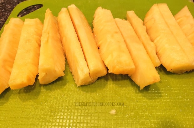 The pineapple is cut into spears to be grilled.