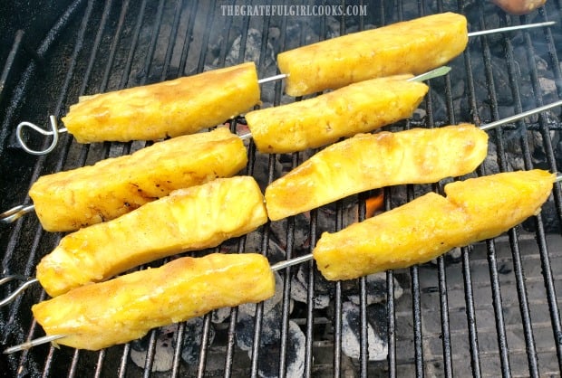 Grilled pineapple skewers cooking over hot coals.