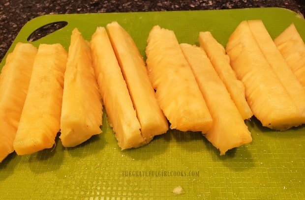 Pineapple spears are cut (or it is cut into chunks), for canning.
