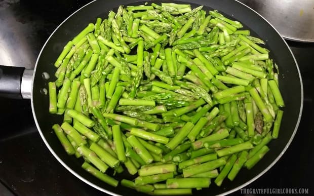 Fresh asparagus is cut and then quick boiled, before placing into canning jars.