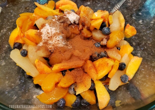 The fruit for the cobbler is mixed with sugar and spices in large bowl.