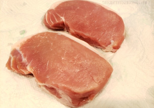 Boneless pork chops are patted dry with paper towels before seasoning is added.