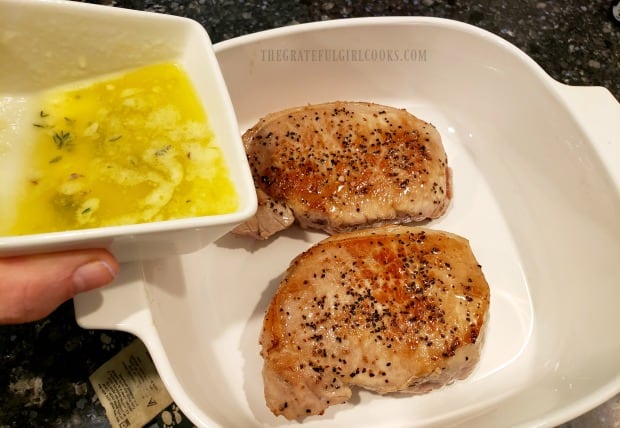 The butter sauce is poured over the top of the chops in a baking pan.