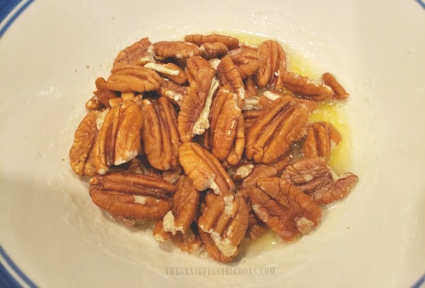 Pecan halves are tossed in melted butter.