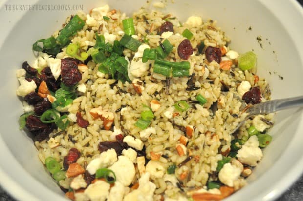 Wild rice, pecans, green onions, cranberries and cauliflower are combined in bowl.