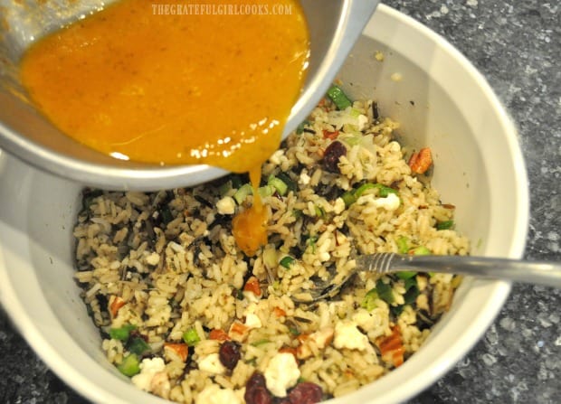 The pumpkin vinaigrette is poured over the wild rice salad, then stirred in.