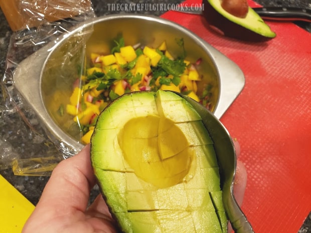 Once cubed, a spoon is used to remove the cubes from the avocado.
