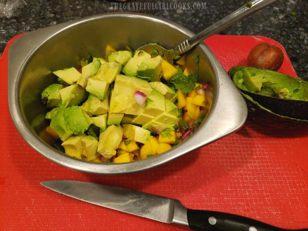 Ingredients for the mango avocado salsa are gently combined before serving.