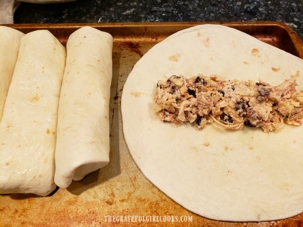Chimichanga filling is placed in middle of a flour tortilla, and then tightly rolled up.