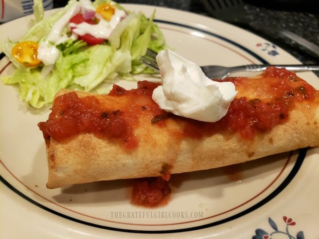 Salsa and sour cream garnish one of the air fryer chicken chimichangas.
