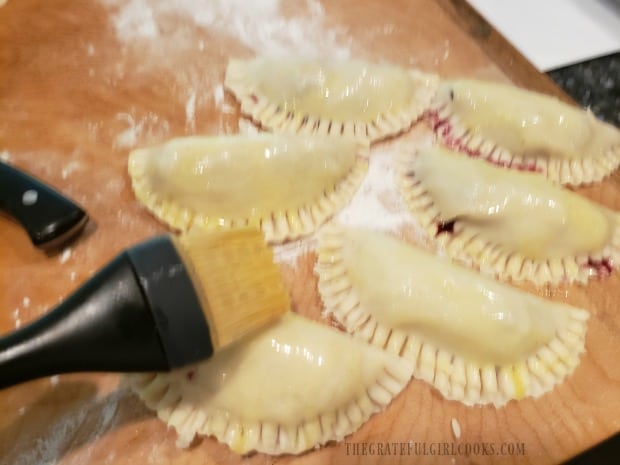 A beaten egg is brushed over the handpies before cooking.
