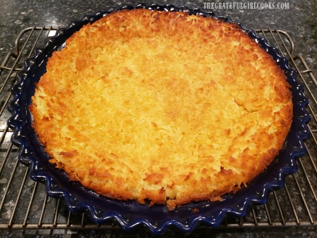 A coconut chocolate chip pie cools in the pie pan, on a wire rack.