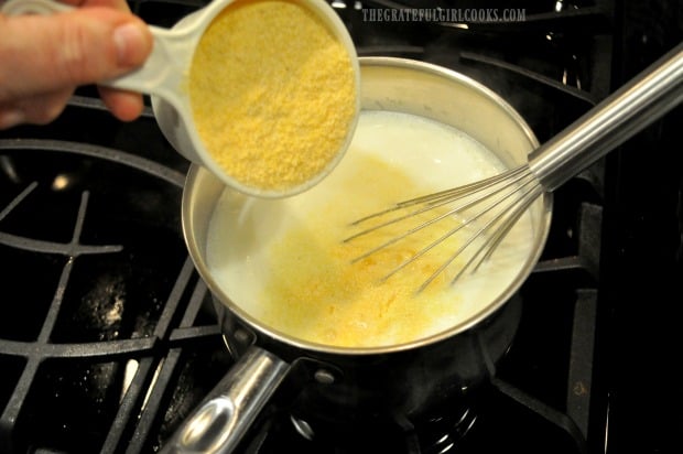 Cornmeal is slowly added and whisked into boiling milk, water and salt in pan.