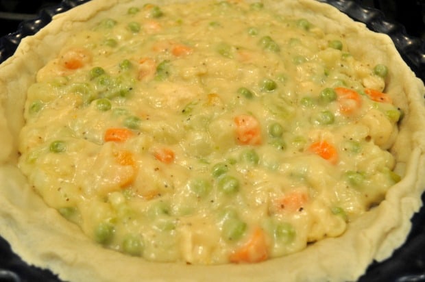The chicken pot pie filling is spread into the pre-baked pie crust.