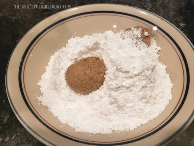 The chilled dough is shaped into balls and coated in powdered sugar.