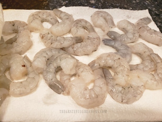 Peeled, de-veined shrimp are patted dry on paper towels before cooking.