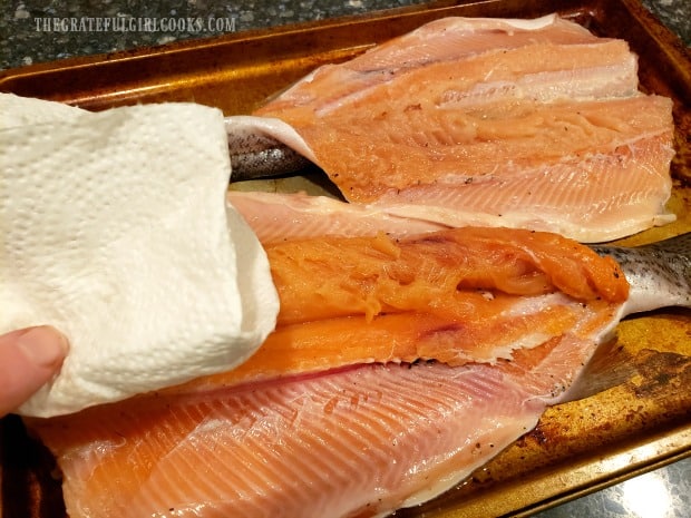 Each trout is patted dry before putting it on the grill for smoking.