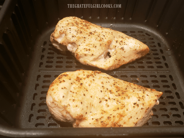 Halfway through cooking time, air fryer chicken breasts are turning golden brown.