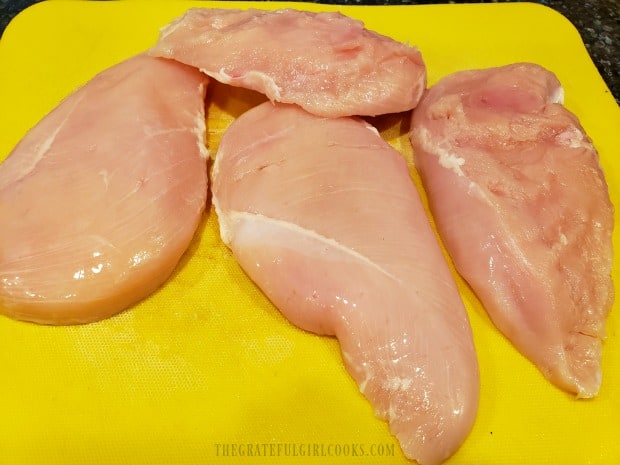 Two large chicken breasts are cut in half horizontally, to create 4 thin pieces of chicken.