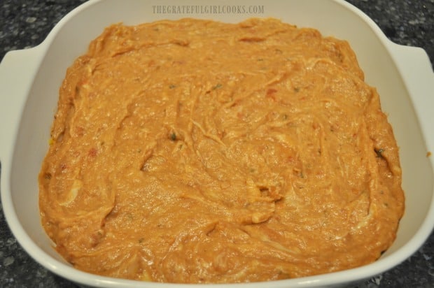 The refried bean mixture is placed on top of the corn chips in dish.