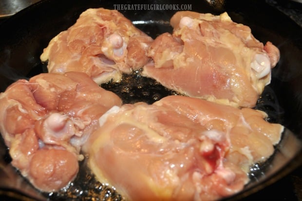 Skinless chicken thighs are browned in hot oil in skillet.