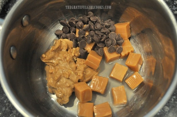 Peanut butter, chocolate chips, water and caramels are cooked in saucepan.