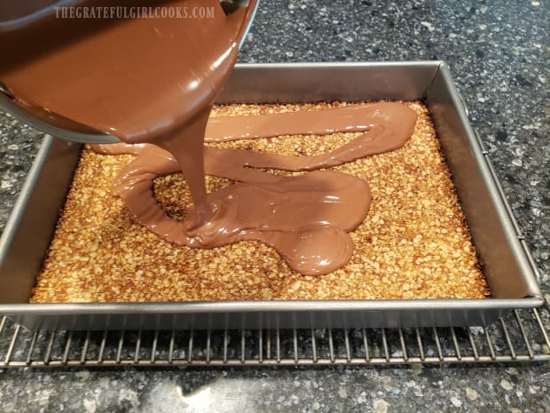 The chocolate peanut butter frosting is poured onto cooled bar cookies, and spread.