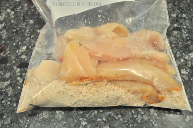 Chicken strips are added to spice mix in plastic bag, and combined to coat.
