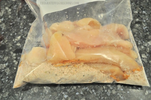 Chicken strips are added to spice mix in plastic bag, and combined to coat.