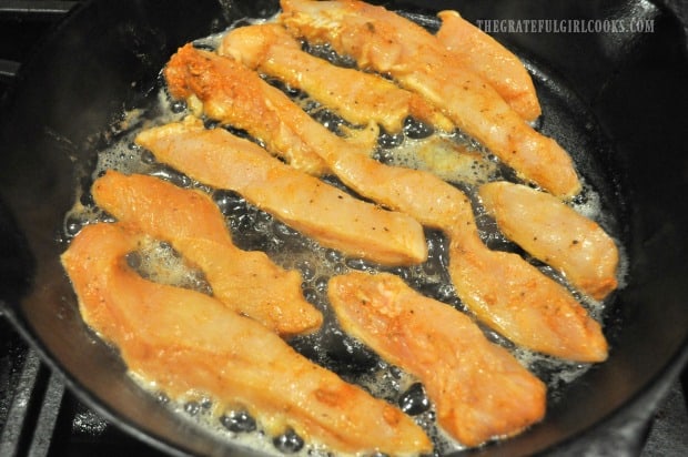Cajun chicken strips are added to the hot skillet to brown.