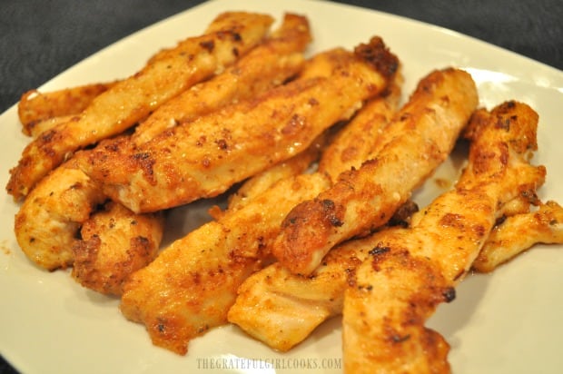 Close up of browned chicken strips with cajun seasoning on a plate.