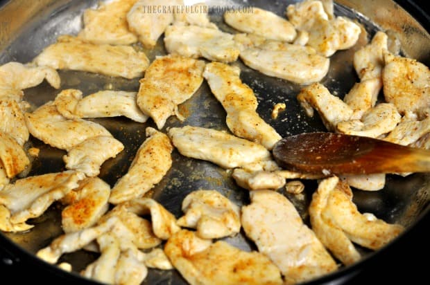 The chicken strips are turned halfway through cooking to brown the other side.