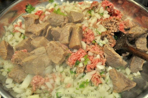 Stew meat, ground beef, onions, and parsley are browned in skillet.