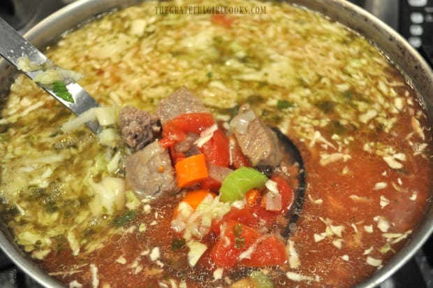 Hearty minestrone soup is cooking away in a large stock pot.