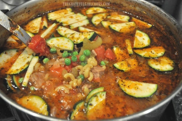 Zucchini, peas, and uncooked macaroni noodles are added to the soup.